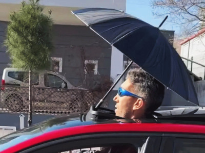 Watch as world’s tallest man Sultan Kosen has to drive with his head out of his SUNROOF & holding a brolly to stay dry